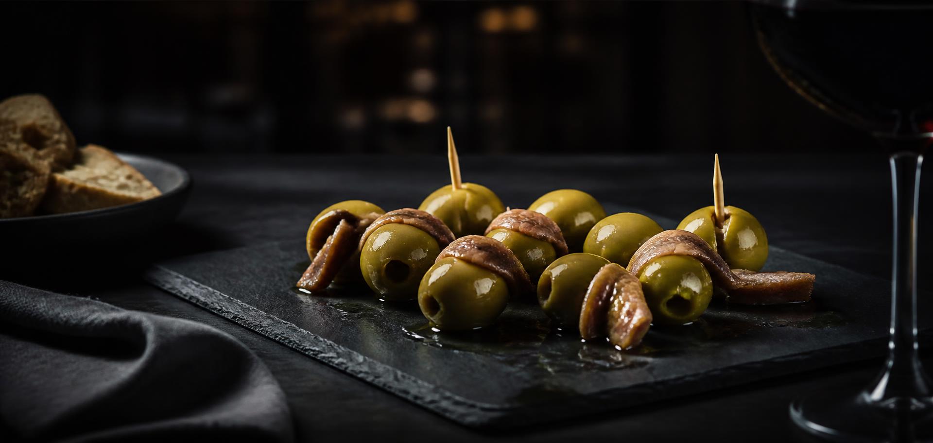 Aceitunas con anchoa servidas sobre pizarra en una mesa de restaurante